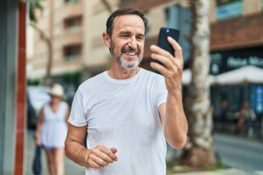 Orta yaşlı bir adam sokakta video araması yaptığından emin gülümsüyor.