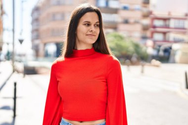 Young beautiful hispanic woman smiling confident looking to the side at street