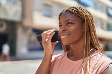 Afro-Amerikalı bir kadın caddedeki akıllı telefondan kendine güvenen bir sesli mesaj dinliyordu.