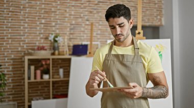 Genç İspanyol sanatçı sanat stüdyosunda palet rengini karıştırıyor.