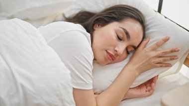 Genç, güzel, İspanyol bir kadın yatakta uzanıyor.