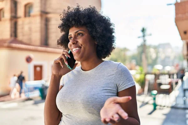 Afro-Amerikalı kadın gülümsüyor. Akıllı telefondan konuşuyor.