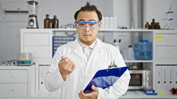 Handsome, young, chinese man, serious adult scientist absorbed in biology analysis, meticulously taking notes on clipboard while speaking passionately about his research in busy lab