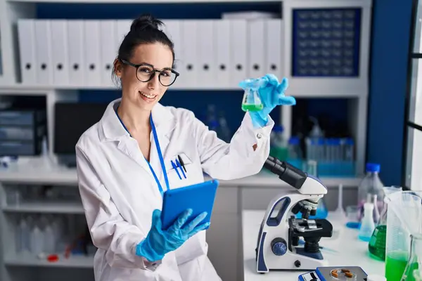 若い白人女性科学者が実験室でタッチパッド保持試験管を使用して — ストック写真