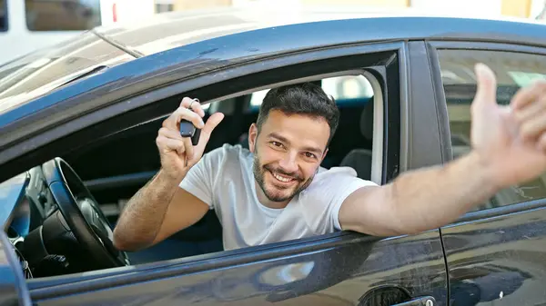 若いヒスパニック男性は ストリートで笑顔で親指を上げる新しい車のキーを保持しています — ストック写真