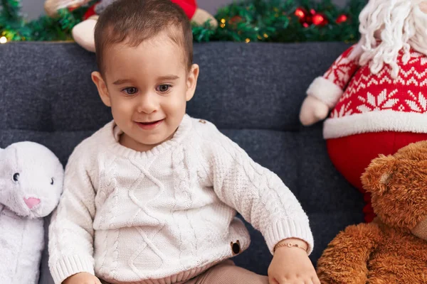 自宅でクリスマスの装飾でソファーに座って自信を持って微笑む愛らしいヒスパニックの幼児 — ストック写真