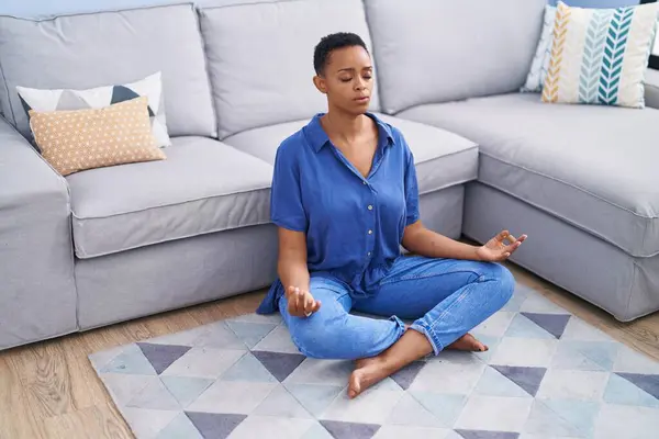 African american woman doing yoga exercise sitting on floor at home