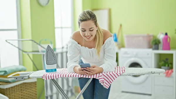 Mujer Rubia Joven Usando Smartphone Apoyado Tabla Planchar Sala Lavandería — Foto de Stock