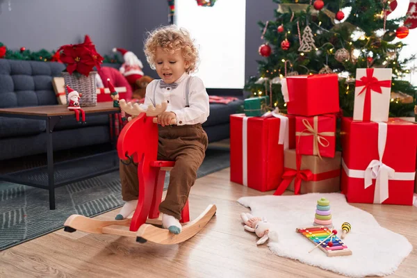 愛らしいブロンド幼児遊びますともにトナカイロッキングによってクリスマスツリーホーム — ストック写真