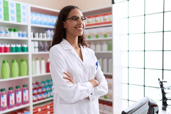 Young african american woman pharmacist smiling confident standing with arms crossed gesture at pharmacy