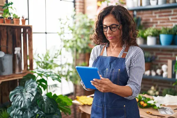 stock image Middle age woman florist using touchpad at flower shop