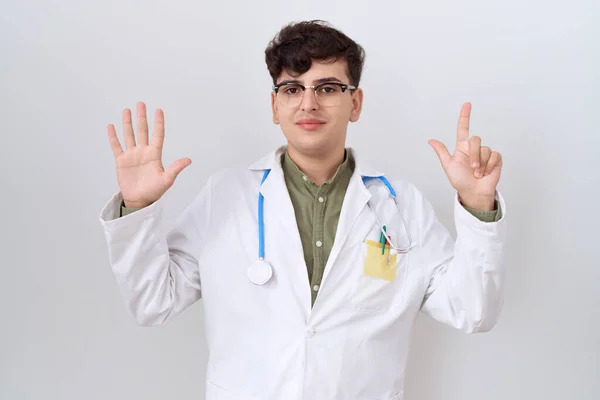 stock image Young non binary man wearing doctor uniform and stethoscope showing and pointing up with fingers number seven while smiling confident and happy. 