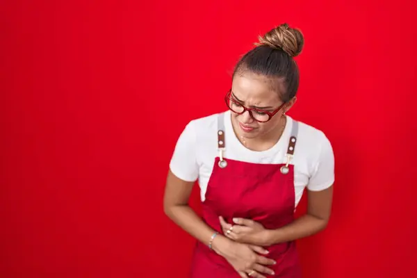 Młoda Latynoska Kobieta Ubrana Fartuch Kelnerki Czerwonym Tle Ręką Brzuchu — Zdjęcie stockowe