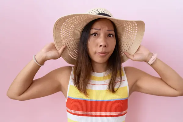 中世の中国人女性は ピンクの背景に懐疑的で神経質な夏の帽子をかぶり 問題のために動揺します ネガティブな人 — ストック写真
