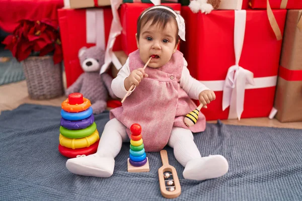 Αξιολάτρευτο Ισπανόφωνο Μωρό Πιπίλισμα Ραβδί Κάθεται Στο Πάτωμα Από Χριστουγεννιάτικα — Φωτογραφία Αρχείου
