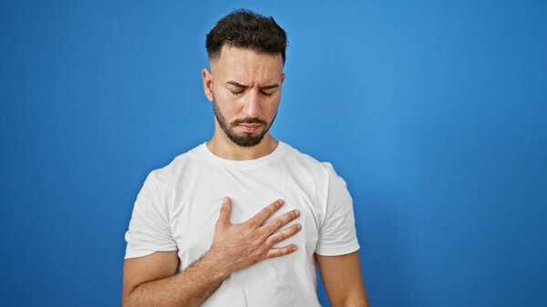 Young arab man suffering heart pain over isolated blue background