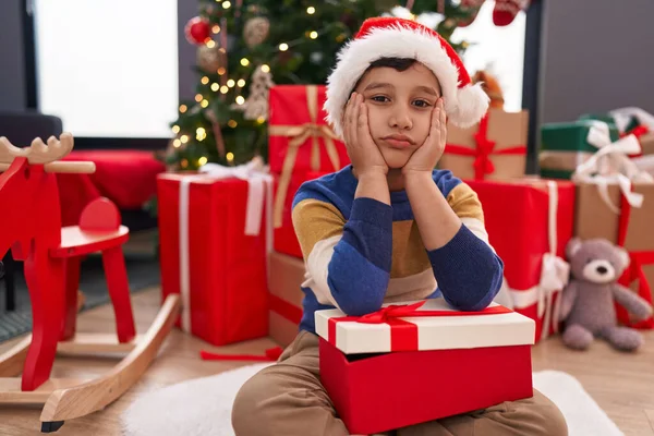 可爱的小男孩带着圣诞礼物坐在地板上 脸上挂着不悦的表情 — 图库照片