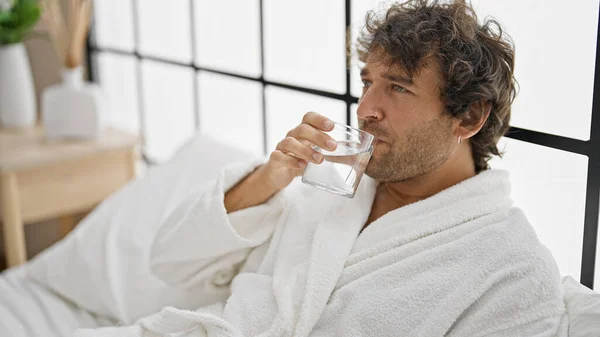 Young Hispanic Man Wearing Bathrobe Drinking Water Bedroom — Stock Photo, Image
