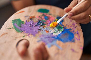 African american man artist mixing color on palette at art studio