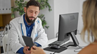 Genç İspanyol doktor klinikteki hastaya dokunmatik ped gösteriyor.