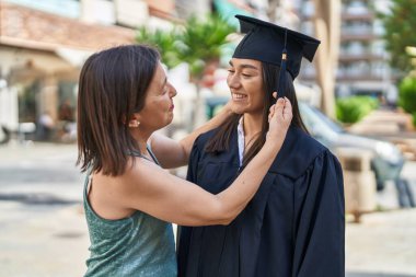 Two women mother and graduated daughter standing together at street