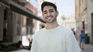Sokakta kendinden emin gülümseyen İspanyol genç adam.