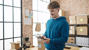 Latin kökenli genç bir iş adamı ofiste gülümseyen bir dokunmatik ped kullanıyor.