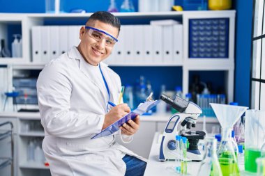 Laboratuvarda çalışan genç Latin bilim adamı rapor yazıyor.