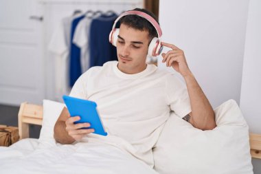 Latin asıllı genç bir adam yatak odasında dokunmatik bir şekilde video izliyor.