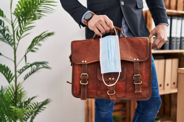 Sağlık maskesi ve evrak çantası taşıyan genç bir iş adamı.