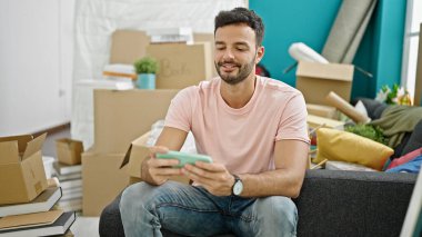 Genç İspanyol adam video oyunu oynuyor. Yeni evine üzgün bakıyor.