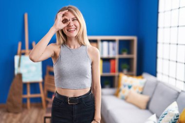 Sarışın, beyaz bir kadın oturma odasında durmuş gülümsüyor. Mutluluktan gülümsüyor. 