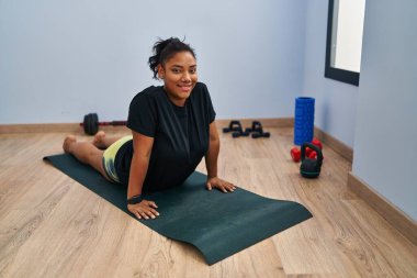 Young beautiful latin woman smiling confident stretching back at sport center