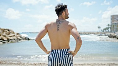 Genç İspanyol turist mayo giyip sahilde dikiliyor.