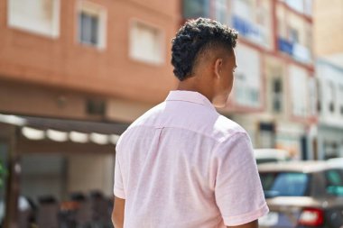 Young latin man standing on back view at street