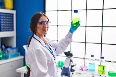 Genç ve güzel İspanyol bilim adamı. Laboratuvarda bir şişe su tutuyor.