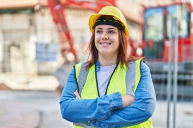 Young beautiful plus size woman architect smiling confident standing with arms crossed gesture at street