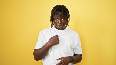 Kendini izole edilmiş sarı arka planda gösteren sürpriz bir ifadeyle Afrika kökenli Amerikalı bir adam.