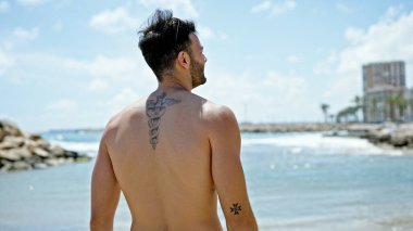 Genç İspanyol turist mayo giyip sahilde dikiliyor.