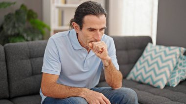 Middle age man sitting on sofa with serious expression at home