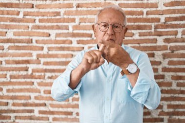 Tuğlaların üzerinde duran gri saçlı son sınıf öğrencisi. Duvarın orada duruyor. Reddedilme ifadesi. 