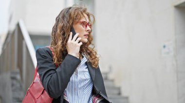 Young woman business worker talking on smartphone at street