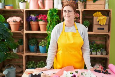 Young beautiful plus size woman florist smiling confident standing at flower shop