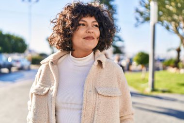 Young beautiful hispanic woman smiling confident looking to the side at street