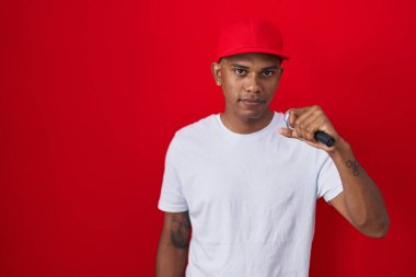 Genç İspanyol adam mikrofon kullanarak şarkı söylüyor. Düşünme tavrı takınıyor ve ayık ifadesi takınıyor. Kendine güveniyor gibi görünüyor. 