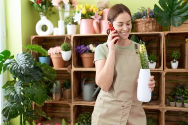 Çiçekçide elinde çiçeklerle konuşan güzel bir kadın.