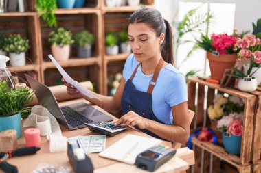 Çiçekçide hesap makinesi kullanan güzel İspanyol bir çiçekçi kadın.