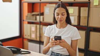 Ofiste gülümseyen akıllı telefon kullanan Afrika kökenli Amerikalı bir iş adamı.