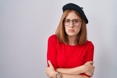 Genç kızıl saçlı, gözlüklü ve bereli bir kadın kış soğuğu için titriyor ve donuyor. Yüzünde üzgün ve şok ifadesi var. 