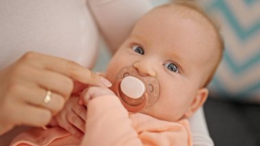 Anne ve kızı kanepede oturmuş emziriyorlar.